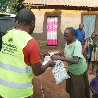 Buwanga volunteers hand sacks of food and a plant to lady