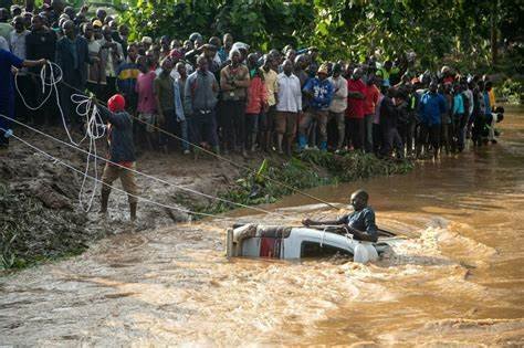 A vehicle is pulled out of a flood, watched by a crowd